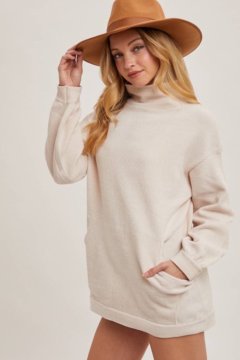 Woman wearing a beige sweater dress and brown hat on a white background