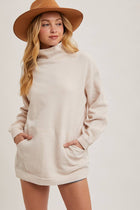 Woman wearing a beige sweater dress and brown hat on a white background