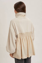 Person wearing a beige tunic with a white background