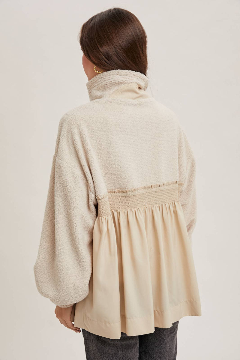 Person wearing a beige tunic with a white background