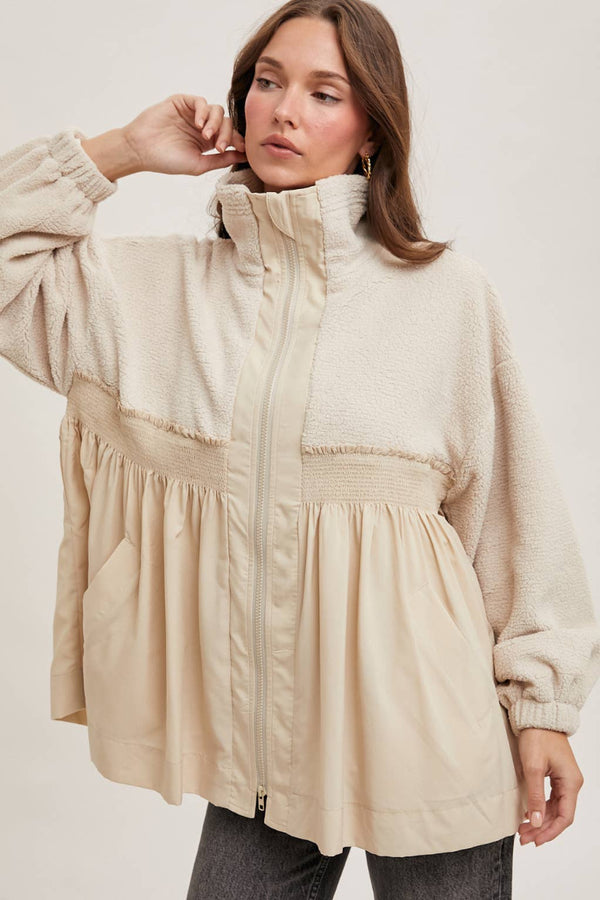Woman wearing a beige puffer jacket on a plain background