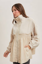 Woman wearing a beige jacket with a white background