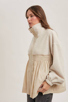Woman wearing a beige sweater with a white background