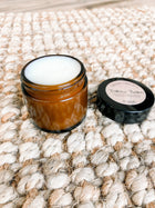 Brown jar with white cream on a textured beige surface