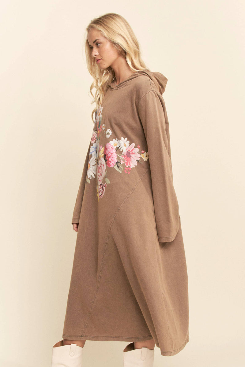 Woman wearing a brown hoodie with floral designs on a beige background