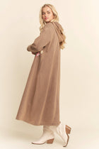 Woman wearing a long brown coat on a beige background