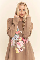 Woman wearing a brown hoodie with floral designs on a beige background