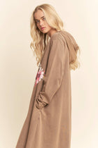 Woman wearing a long brown coat with a floral design on a beige background