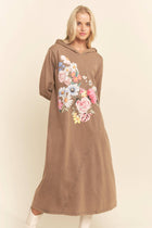 Woman wearing a brown hoodie dress with floral design on a plain background